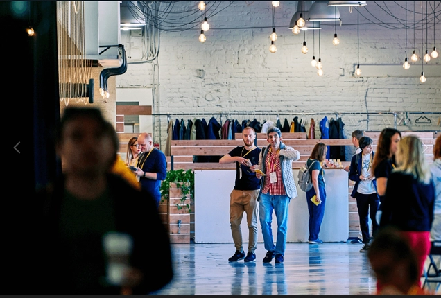 Attendees networking in a conference venue with a casual atmosphere and hanging lights.
