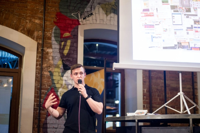 Speaker presenting in front of a projected screen during an event.