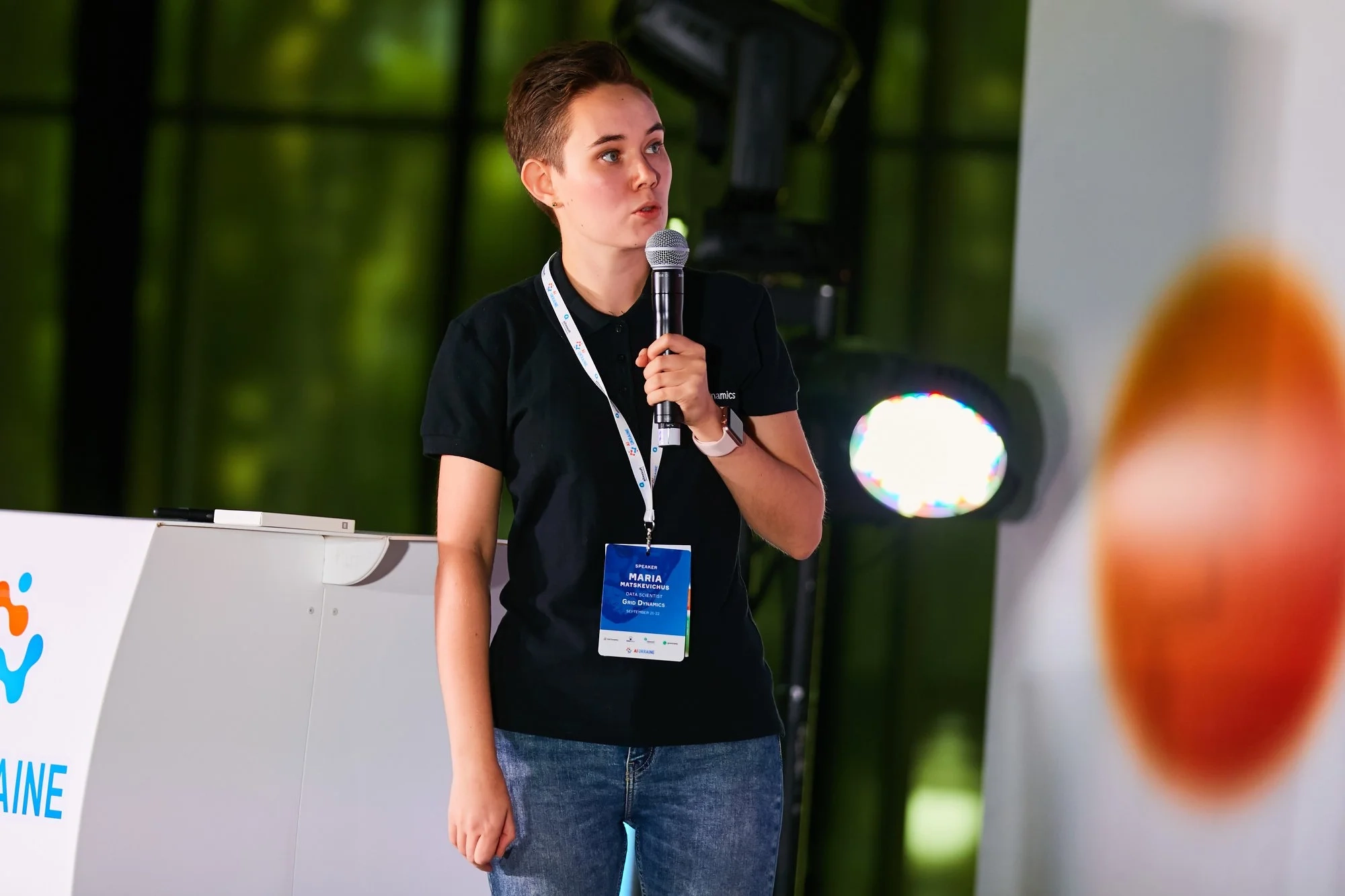 Person holding a microphone and giving a presentation at a conference.