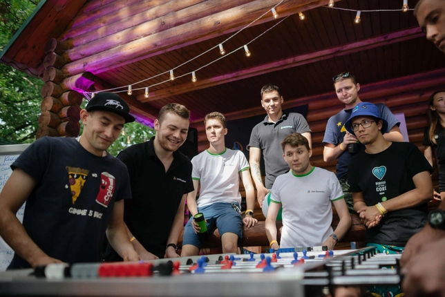 Group of colleagues enjoying a foosball game outdoors during a team event.