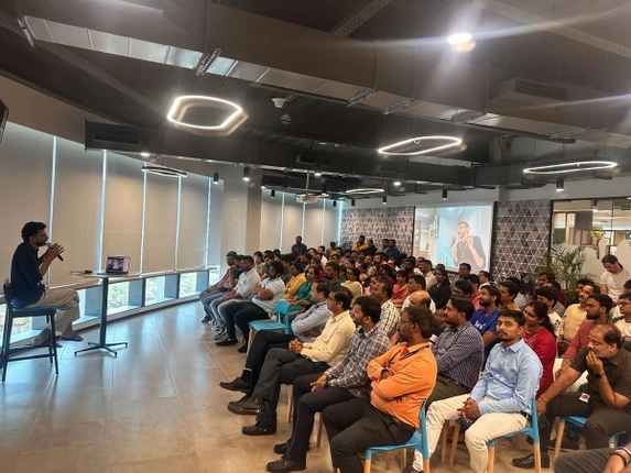 Speaker addressing a large audience in a modern conference room.