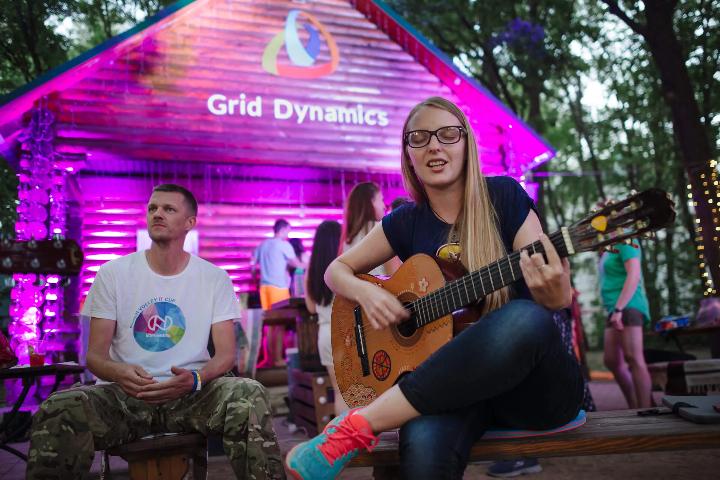 Person playing guitar with Grid Dynamics logo in the background.