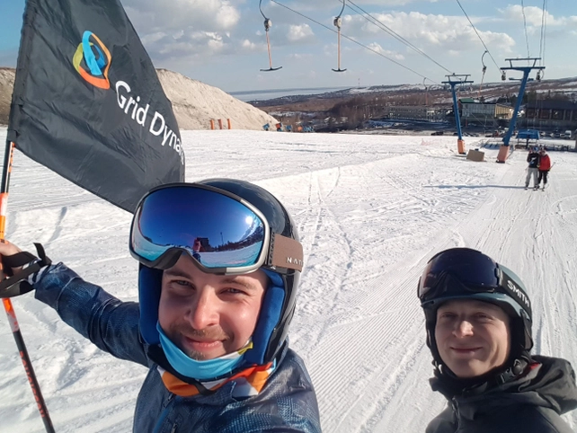 Two skiers holding a Grid Dynamics flag