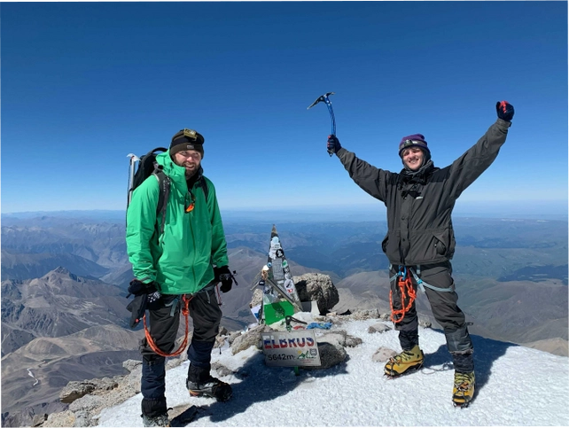 Two climbers celebrating at the snowy summit of Mount Elbrus