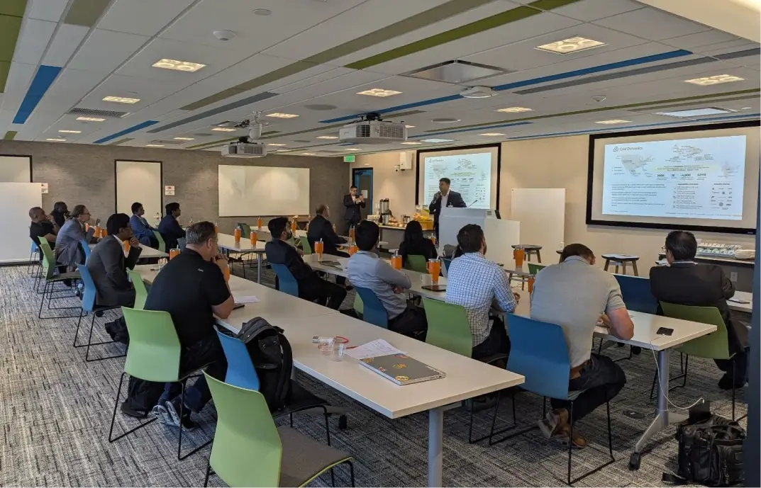People attending a presentation in a conference room with multiple screens displaying information